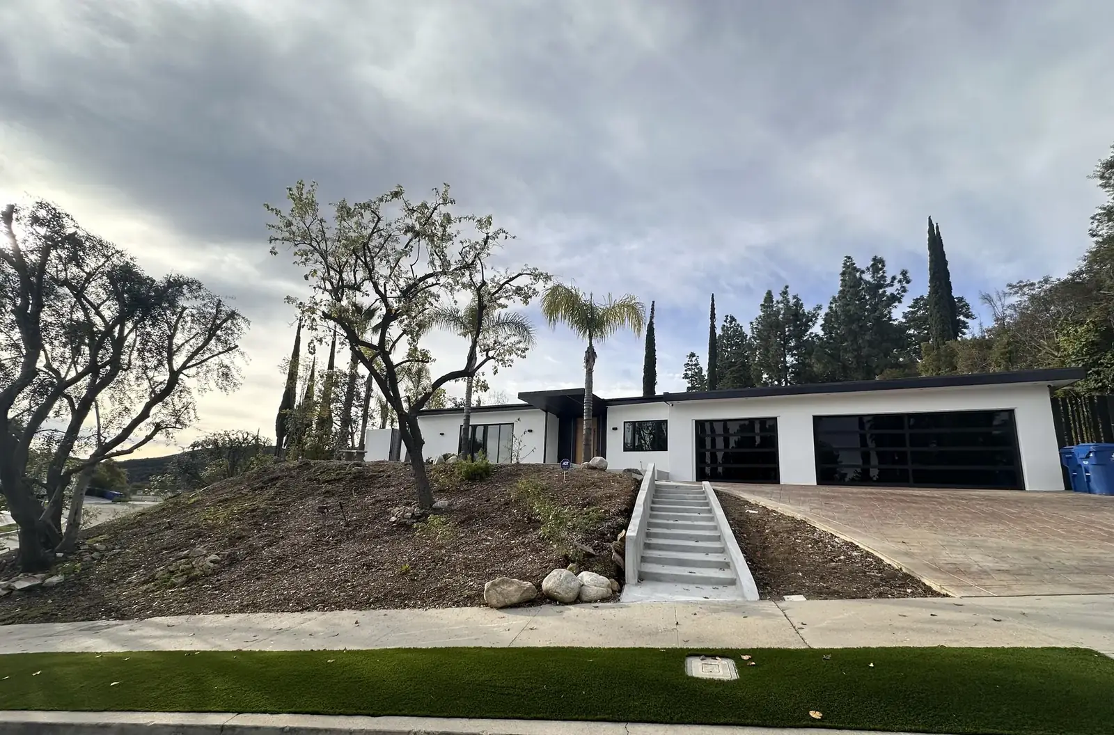 Renovated Encino hillside home with white exterior, black window frames and glass garage doors