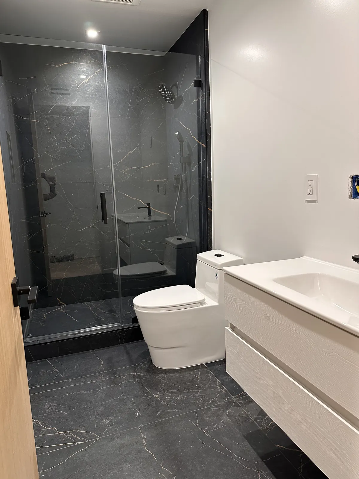 Bathroom with dark marble shower and floating vanity