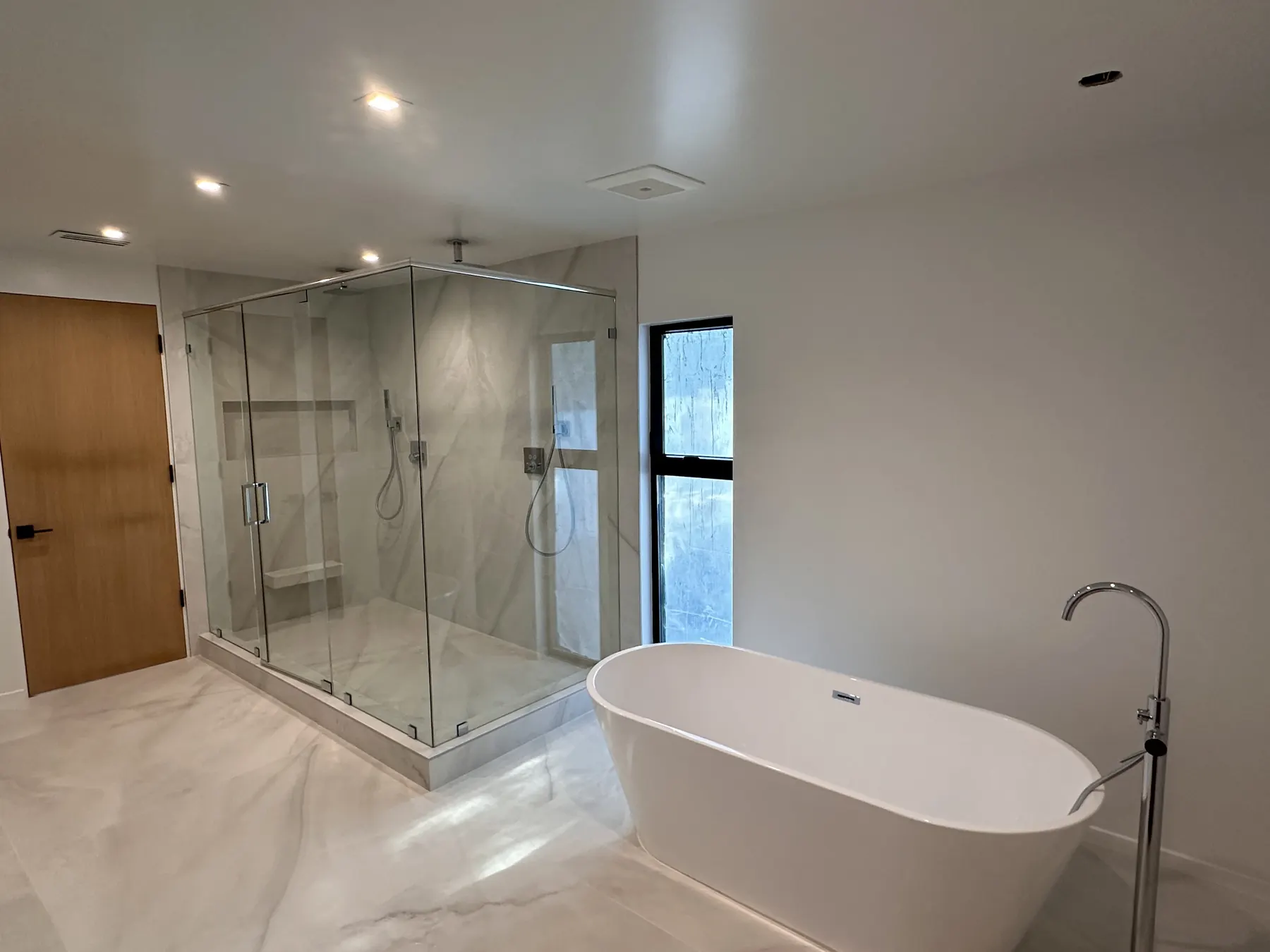 Renovated master bath with freestanding tub and glass shower