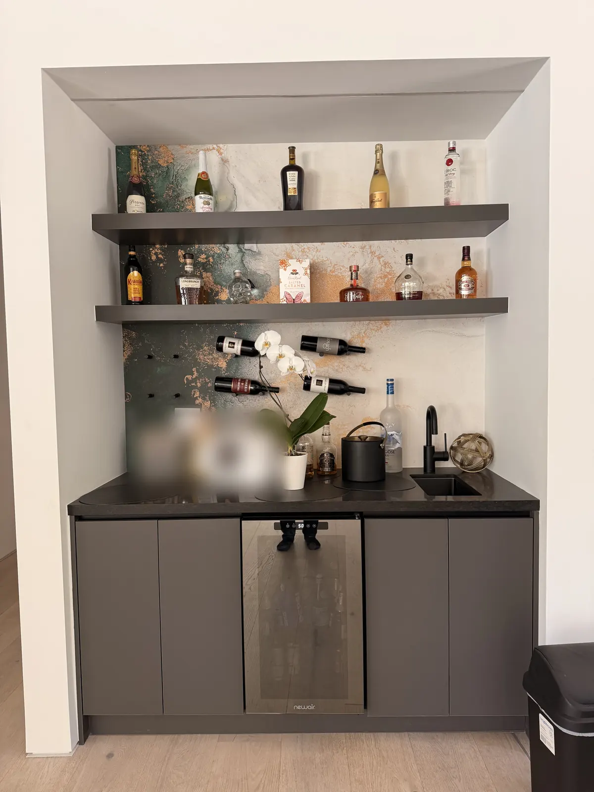 Wet bar with open shelving and dark cabinetry