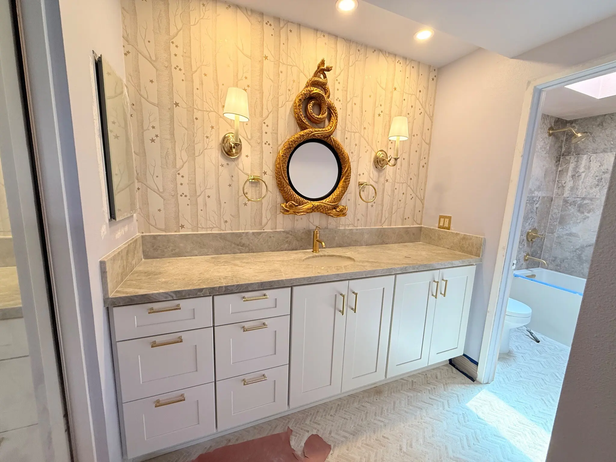 Completed Irvine bathroom with custom vanity, stone counter, wall covering, and brass details