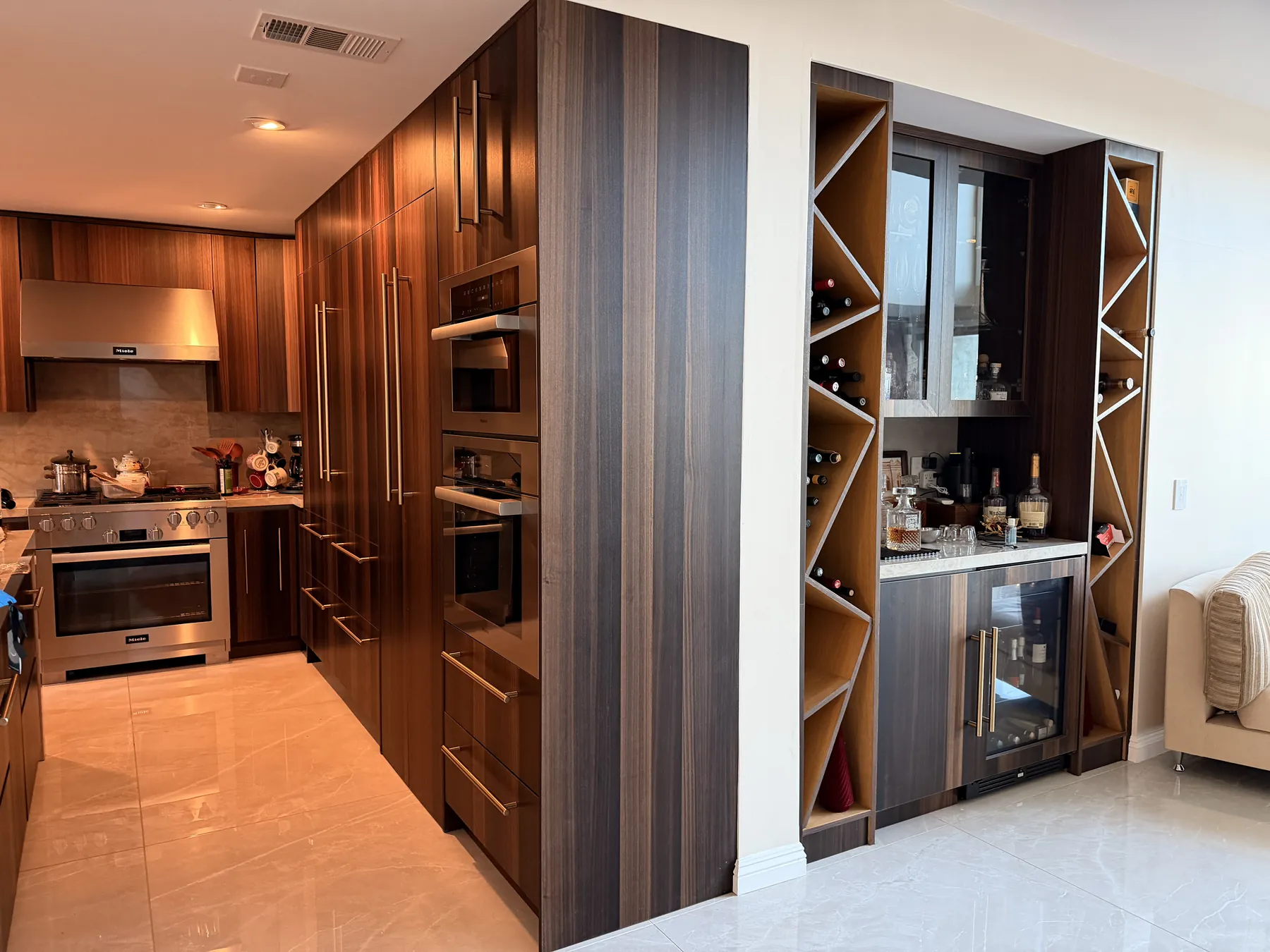Remodeled kitchen with walnut cabinetry, built-in ovens and a wine and bar wall