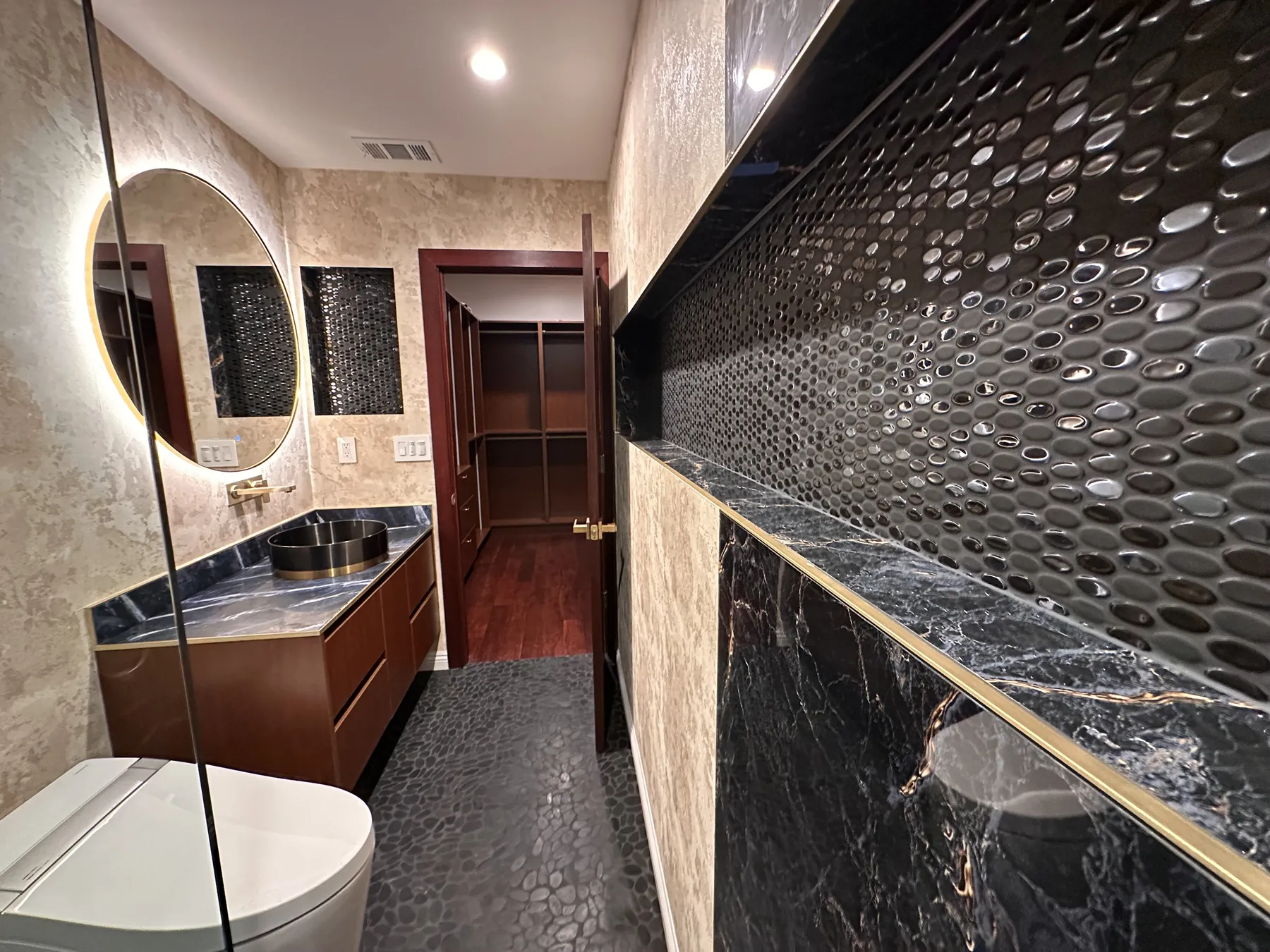 Bathroom with black penny tile and a pebble floor